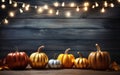 Autumn pumpkins background with copy space, garland with light bulbs, dark bokeh lights, maple leaves. Wooden table. Halloween Royalty Free Stock Photo