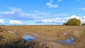 In autumn, after the rain, puddles formed on the country road, reflecting the blue sky with clouds. The tracks of car tires were i