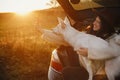 Autumn road trip with pet. Stylish hipster woman taking selfie photo with cute dog in car trunk in warm sunset light. Young female Royalty Free Stock Photo