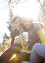 Autumn Romance. A romantic young couple sitting close together while enjoying some coffee in the outdoors.