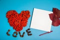 Paper blank, pen, heart made of Rowan berries, acorns, red leaves on a light blue background. Royalty Free Stock Photo