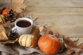 Autumn rural banner. Warm cup of tea, pumpkins, fall leaves, cozy scarf on rustic wooden table with space for text. Hygge autumn. Royalty Free Stock Photo