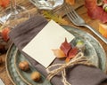 Autumn rustic table setting with blank place card between colorful leaves and berries close up, mockup