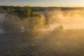 Autumn scene in morning sunlight on misty riverside. Bright warm sun light through fog and trees aerial view. Beautiful october Royalty Free Stock Photo