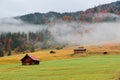 Autumn scenery of Bavarian countryside in morning fog, with wooden barns on the grassy field by the hillside Royalty Free Stock Photo