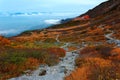 Autumn scenery of beautiful Senjojiki Cirque with a hotel by withered bushes on a grassy mountainside and majestic foggy mountains