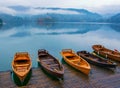 Autumn scenery with boats moored on Bled lake at foggy day Royalty Free Stock Photo