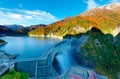 Autumn scenery of Kurobe Dam on a brisk sunny day, in Tateyama Kurobe Alpine Route, Japan, with beautiful fall foliage on lakeside