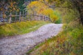 Autumn scenery landscape with rural road, colorful forest, wood fences and hay barns in Bucovina Royalty Free Stock Photo