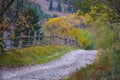 Autumn scenery landscape with rural road, colorful forest, wood fences and hay barns in Bucovina Royalty Free Stock Photo