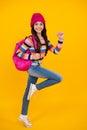 Autumn school. Teenager school girl with backpack in autumn clothes on yellow studio background. Jump and run