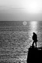 Fisherman fishing on sea pier in black and white