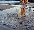 Autumn seashore. A child girl jumps barefoot through the sea puddles. Children`s rest. Happy moments of child