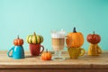 Autumn season creative concept with latte macchiato coffee cup and pumpkin decor on wooden table Royalty Free Stock Photo