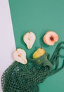 Autumn season minimalist scene. Organic pears, peach and mesh bag on green and white background. Zero waste, bio, eco, vegan Royalty Free Stock Photo