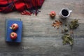 Autumn season still life with red apples, books, red plaid blanket, black coffee cup and fall leaves over rustic wooden background