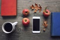 Autumn season still life with red apples, books, mobile device, black coffee cup and fall leaves over rustic wooden background. Kn Royalty Free Stock Photo