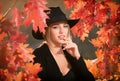 Autumn sensual woman with yellow maple leaves. Closeup portrait of a beautiful sensual girl in black hat near colorful Royalty Free Stock Photo