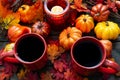 Autumn setting with small pumpkins and a red candle holder emitting light on two cups of morning coffee
