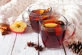 Autumn spiced tea with apples and pomegranates, side view against white wood background with cozy blanket