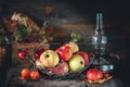 Autumn still life of apples in a basket with a lamp and candles. Royalty Free Stock Photo