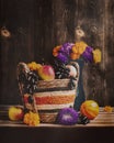 Autumn still life with apples and grapes in a basket. Purple asters and marigolds in a blue vase, pumpkin on a dark background. Royalty Free Stock Photo