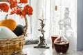 Autumn still life. Basket with pumpkins, candlestick with a candle and decanter with red wine on windowsill during the Royalty Free Stock Photo