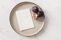 Autumn still life. Blank greeting card mockup, cut figs fruit and ceramic plate on white marble table background. Fall Royalty Free Stock Photo