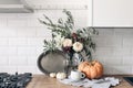 Autumn still life composition in rustic eclectic kitchen interior. Cup of coffee, vintage silver tray and floral bouquet