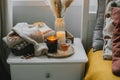 Autumn still life concept. Cozy aututmn composition with burning candles, glass cup of tea, stack warm sweaters