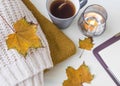 Autumn still life cozy items with woolen sweaters, candle, tea a