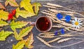 Autumn still life with a cup of tea, maple leaves, ears of wheat, cornflowers on a rustic wooden background.