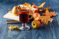 Autumn still life : mulled wine with cinnamon, pear, autumn leaves, books and apple on a wooden background