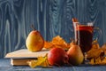 Autumn still life : mulled wine with cinnamon, pear, autumn leaves, books and apple on a wooden background