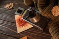 Autumn still life with an old camera, sweater, photos and fallen leaves on wooden background