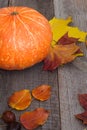 Autumn still life. Pumpkin and dry leaves on wooden board. Top view. Royalty Free Stock Photo