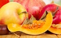 Autumn still life of red apples and slices ripe pumpkins on the abstract green background. Royalty Free Stock Photo