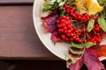 Autumn still life. Rowan, viburnum, apples. Fruits and berries on a wooden plate. background of autumn leaves.Red Royalty Free Stock Photo