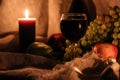 Autumn still life. Thanksgiving post card. Glass full of red wine with candle light reflection and fruits on background Royalty Free Stock Photo