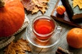 Autumn still life on a wooden table with a cup of tea, pumpkin and fallen leaves, thanksgiving layout warm cozy mood