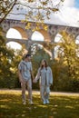 Autumn Stroll: Loving Couple Hand in Hand by Vintage Bridge in the Park. romantic escapade, autumn love, historical Royalty Free Stock Photo