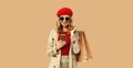 Autumn style outfit, portrait of stylish smiling young woman model with mobile phone holds shopping bags wearing red french beret Royalty Free Stock Photo