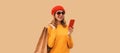 Autumn style outfit, portrait of stylish smiling young woman model with mobile phone holds shopping bags wearing red french beret Royalty Free Stock Photo