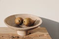 Autumn, summer fruit food still life. Couple of yellow pears, wooden bowl on table in sunset light. Blurred beige wall