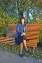 Autumn sunny day in the evening in the park, a young lady sits on a park bench, colorful autumn leaves create an incredibly cozy