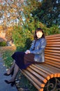 Autumn sunny day in the evening in the park, a young lady sits on a park bench, colorful autumn leaves create an incredibly cozy