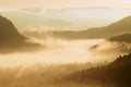 Autumn sunrise. Beautiful mountain of Bohemia. Treetops and peaks of hills increased from yellow and orange fog striped due to str Royalty Free Stock Photo