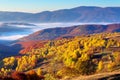 Autumn sunrise in mountainous countryside. trees in golden foliage on the meadow in weathered grass. distant valley full of fog. Royalty Free Stock Photo