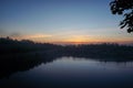 Autumn sunrise near park lake in city, colorful sky is mirroring