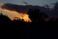 Autumn sunset over the village: silhouettes of houses, pillars, trees against the background of a dark golden autumn sky Royalty Free Stock Photo